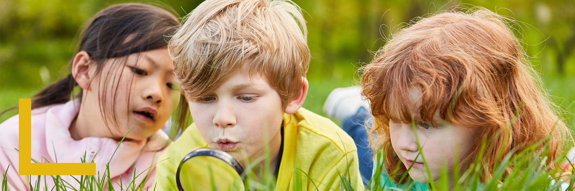 3 kids discovering nature where one holds a magnifying lens