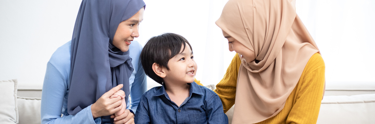 A toddler sits in between two caring women