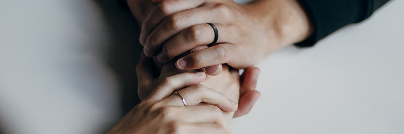 Close-up of two hands holding each other on a table-top